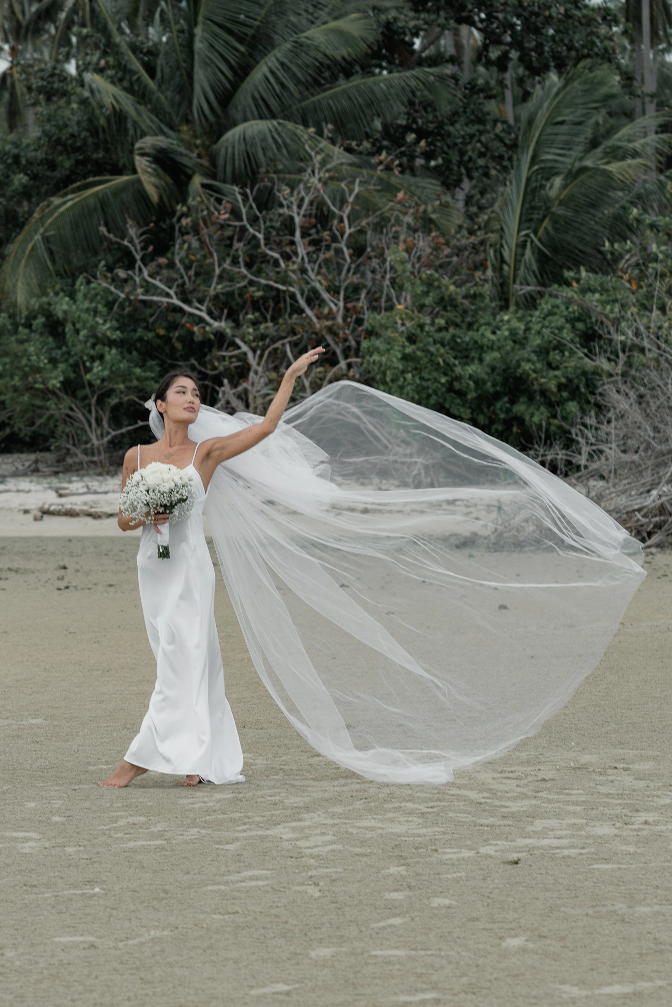 Bride and groom framed beneath a flowing veil