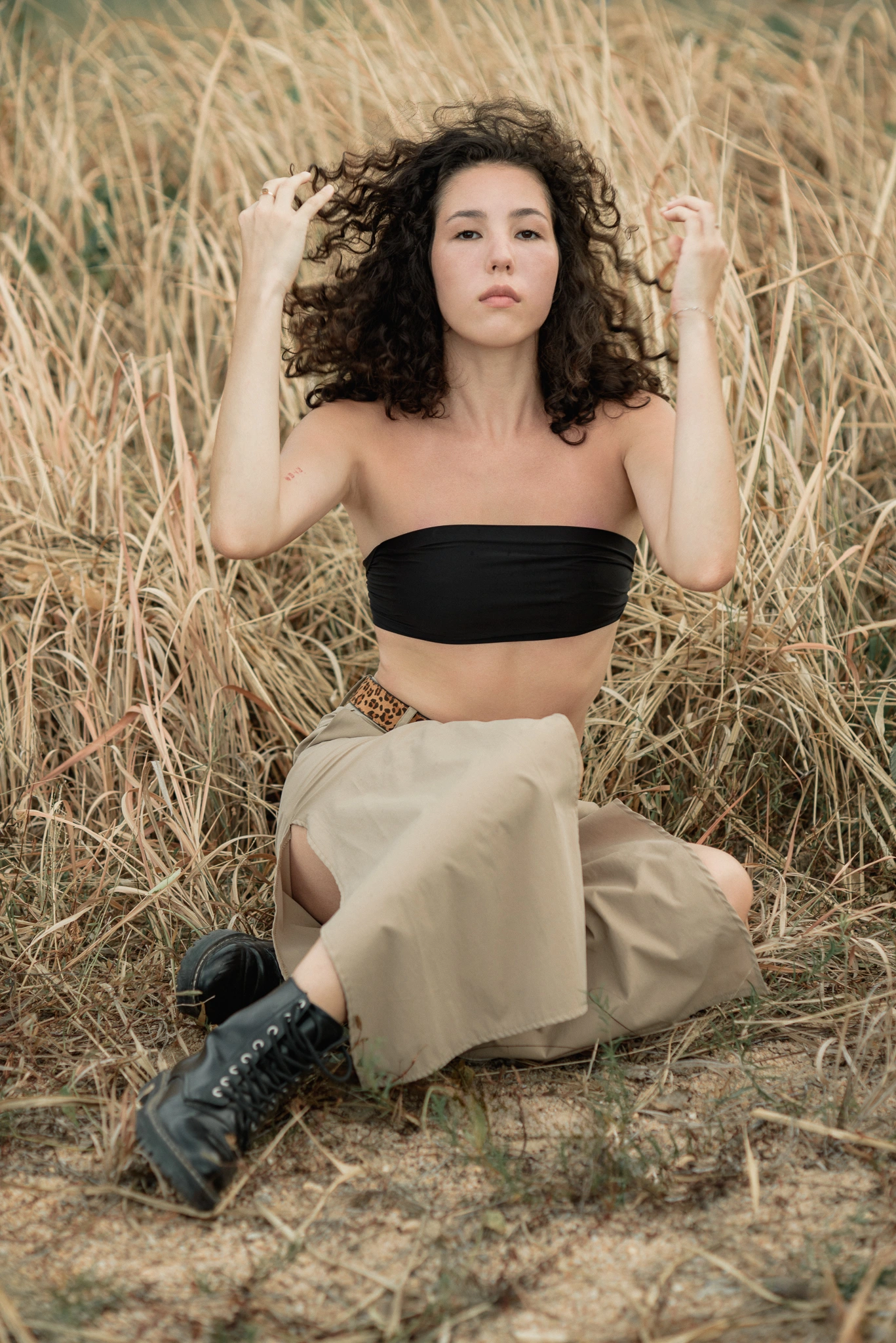 Seated fashion pose among sunlit grasses