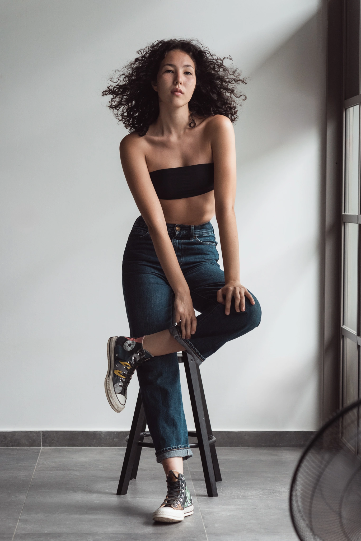 Model seated on a stool in natural window light